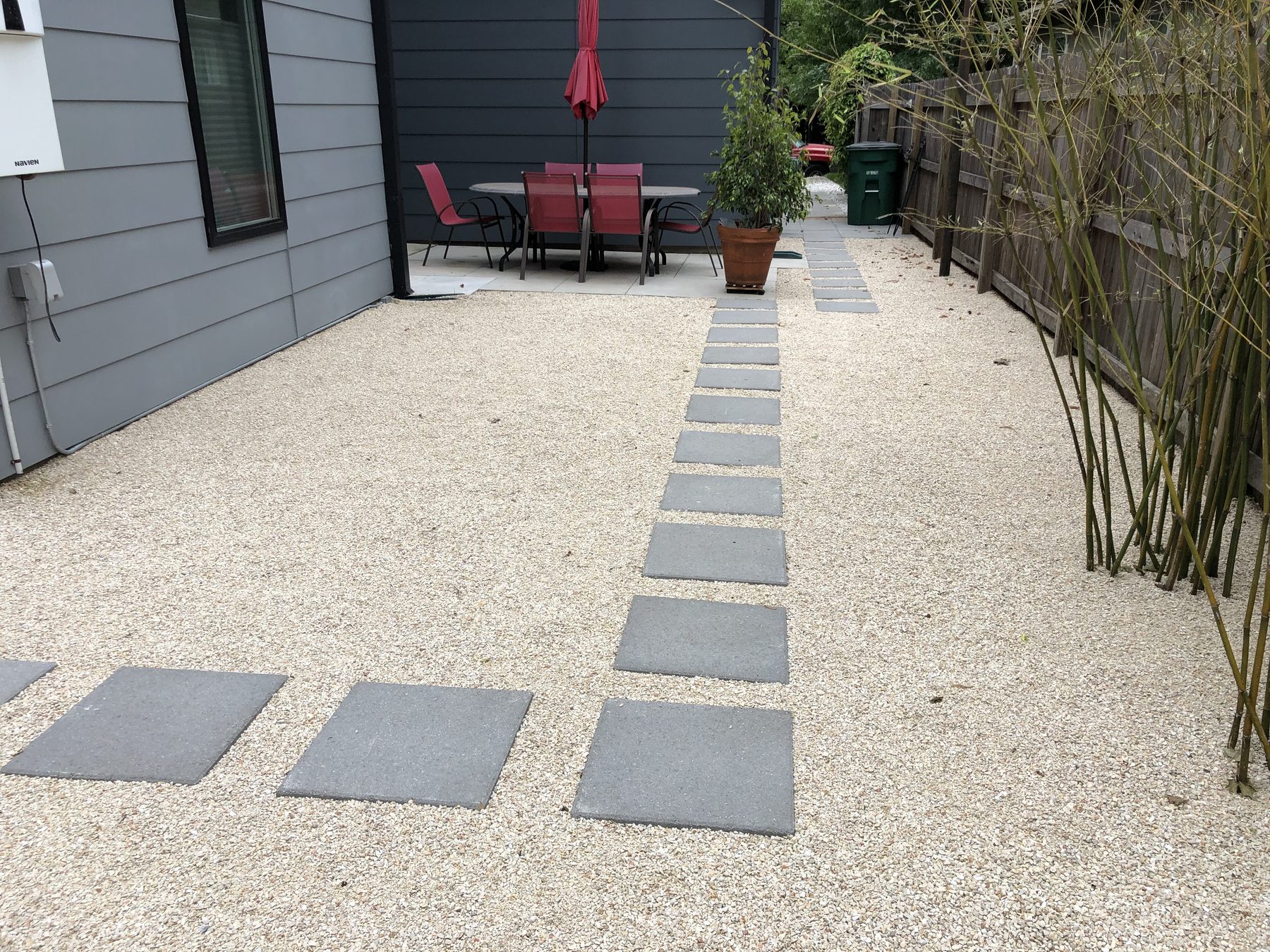 Light gravel yard with square pavers leading to a small patio