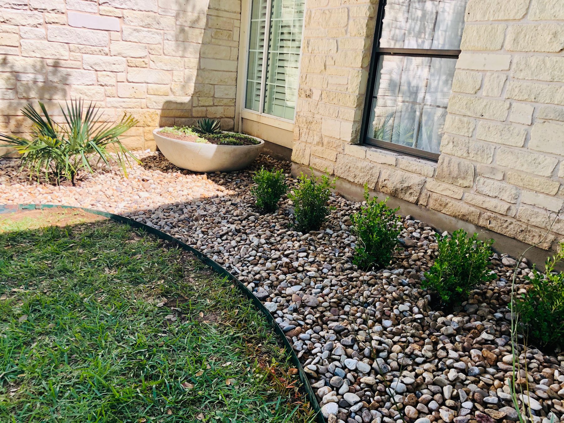 River-rock bed along a limestone house wall